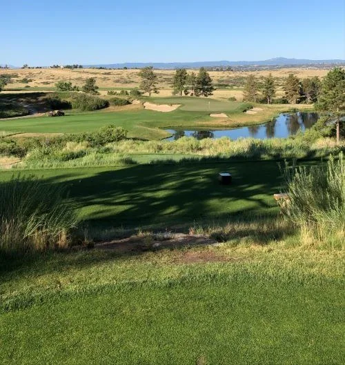 Golf course landscape with a pond and distant mountains