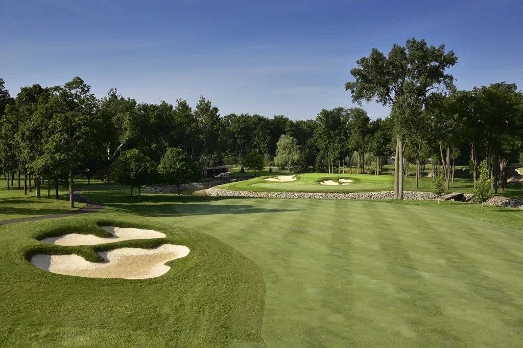 Manicured golf hole with bunkers and a water feature